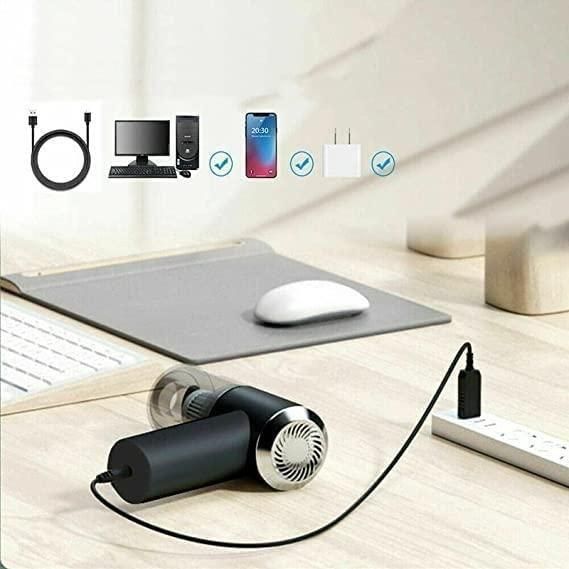 Black handheld device with charging cable on a desk with electronic devices and icons in the background