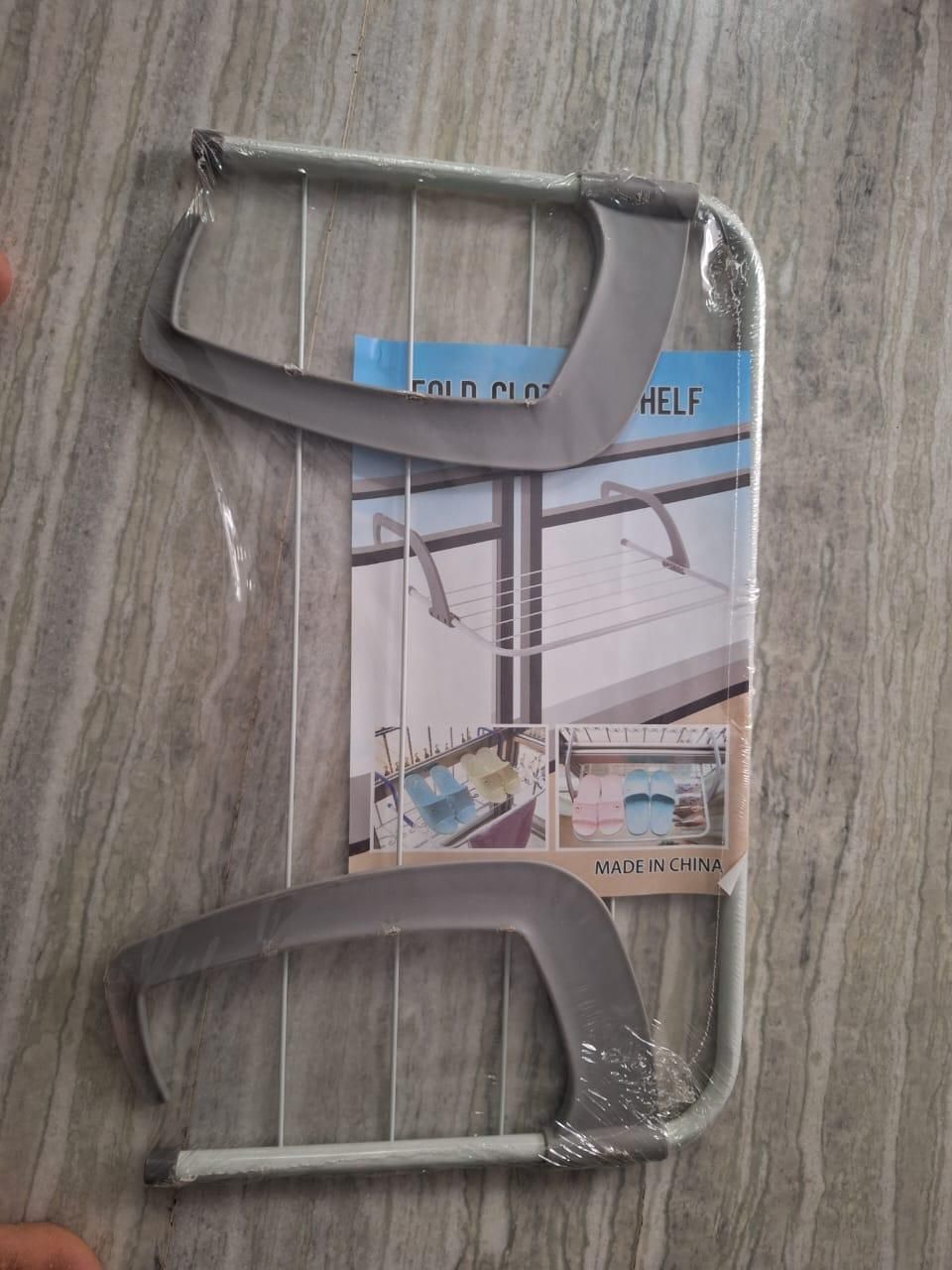 Gray metal clothes rack on a wooden surface with packaging in the background.