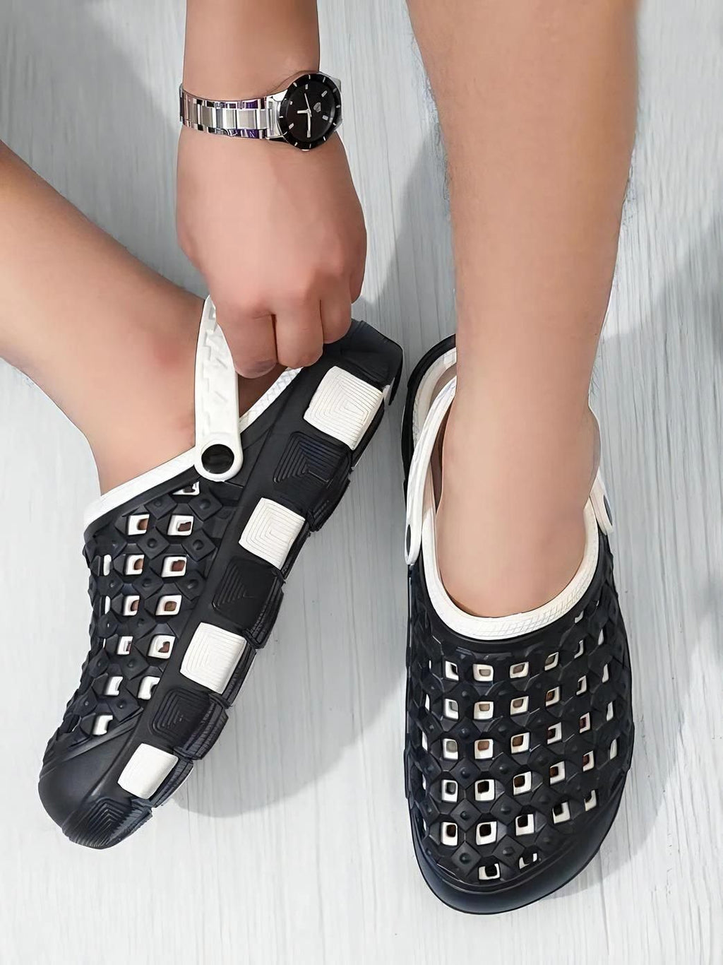Black sandals with white accents worn by a person on a light gray background
