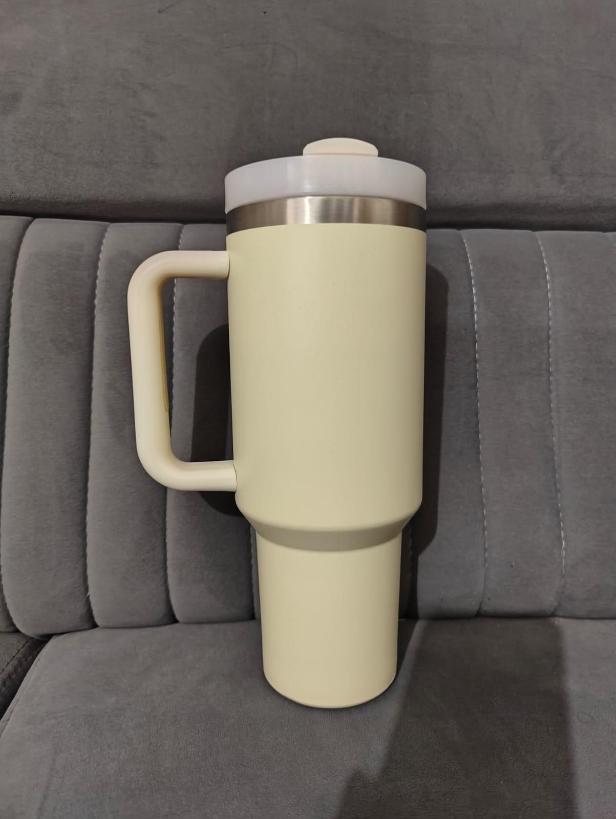 Beige travel mug with a silver lid on a gray couch
