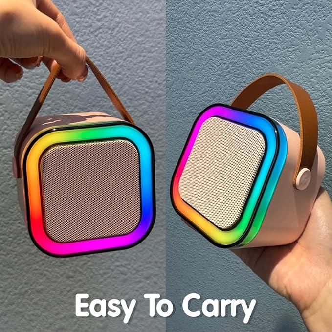 Colorful portable speaker with carrying handle held by a hand against a gray background.