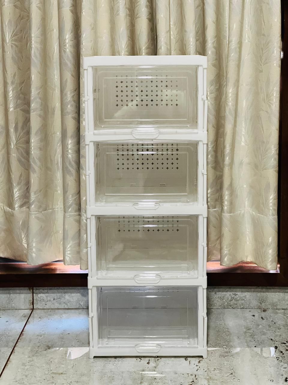 Stack of white plastic crates against a beige curtain background
